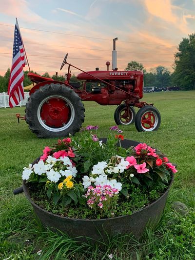 Antique tractor with American flag behind colorful flower pot