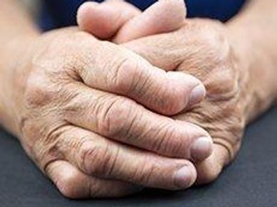 Close-up of wrinkled hands clasped together.