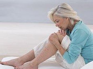 Woman examining her painful knee while sitting on the floor.
