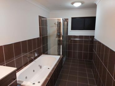 Modern bathroom with brown tiles, a bathtub, and a glass shower enclosure.