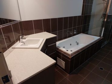 Modern bathroom with a white sink and a dark tiled bathtub.