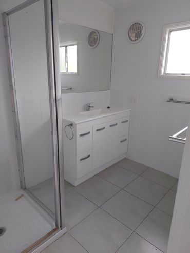 Minimalist white bathroom with shower, vanity, and large mirror.