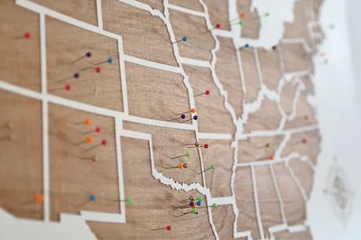 Wooden US map with colorful pins.