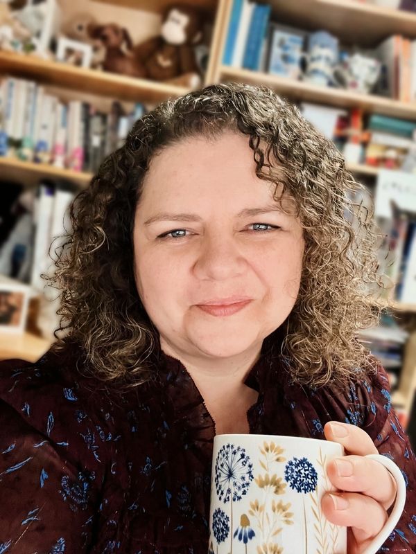 Woman smiling at the camera with dandelion mug of tea