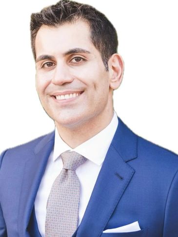 Smiling man in a blue suit and patterned tie.