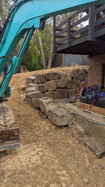 A Mudstone retaining wall under construction with a Kobelco Excavator