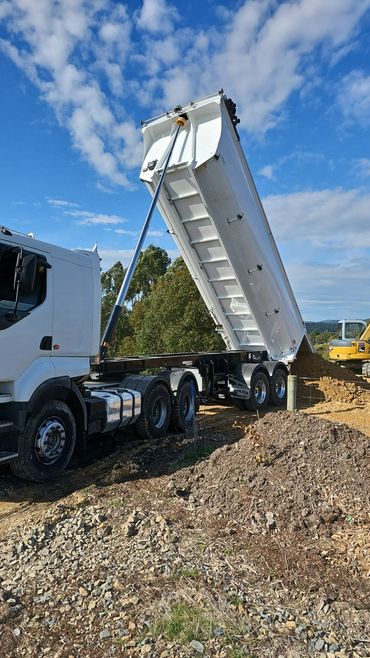 A semi tipper unloading soil on a job site.