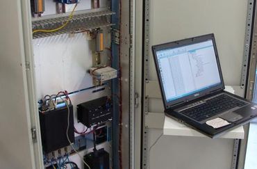Laptop computer diagnosing open electrical cabinet.