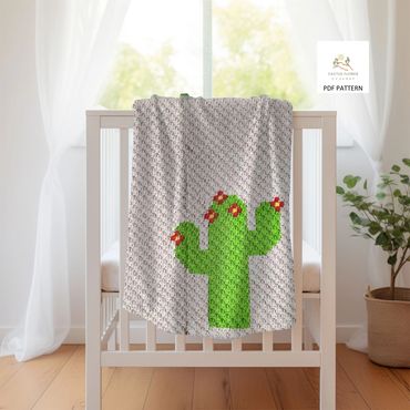 baby blanket with a small green saguaro with red and yellow flowers hanging on the edge of a crib