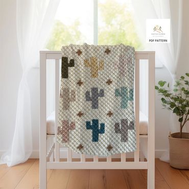 baby blanket with multiple small saguaros, hangng on the edge of a crib