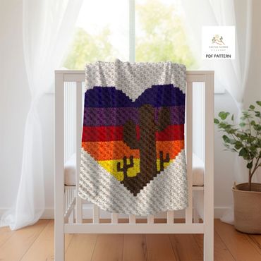 baby blanket with a large heart with multiple colored stripes and 3 saguaros, hangng on a crib