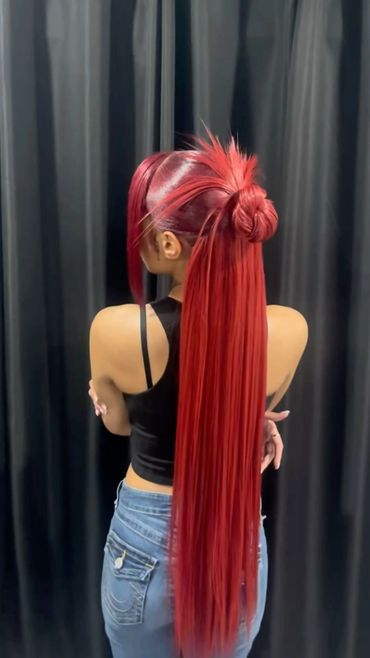 Woman with vibrant red hair styled in a sleek ponytail and bun.