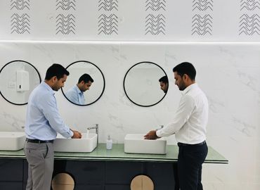 Two men washing hands in a modern restroom with round mirrors.