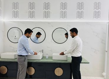 Two men washing hands in a modern restroom with round mirrors.