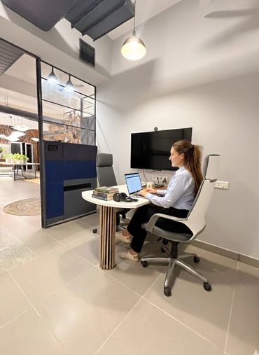 Woman working on a laptop in a modern office meeting room.