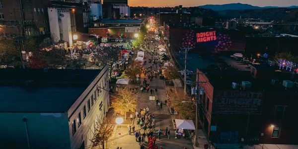 A nighttime street festival with crowds and bright lights.