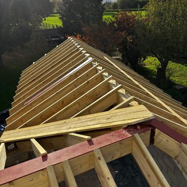 Wooden roof framework under construction on a sunny day.