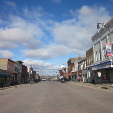 Empty street lined with old buildings under a cloudy sky.