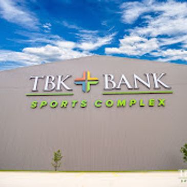 Exterior view of TBK Bank Sports Complex with a bright blue sky.