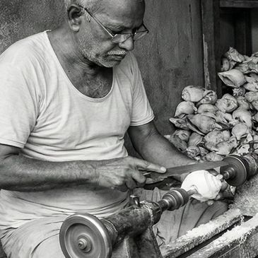 Older man carving wood on a lathe machine.