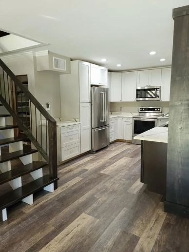 Modern kitchen with wooden flooring and stainless steel appliances.