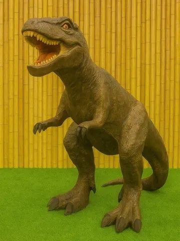 A realistic T-Rex dinosaur model with an open mouth against a bamboo wall.
