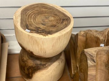 Polished wooden stools and trays with natural grain patterns on tiled floor.