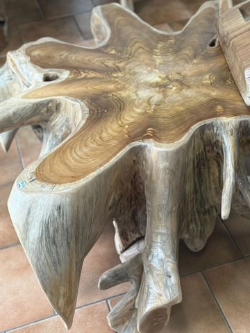 Natural wood table with a bottle of wine on tile flooring.
