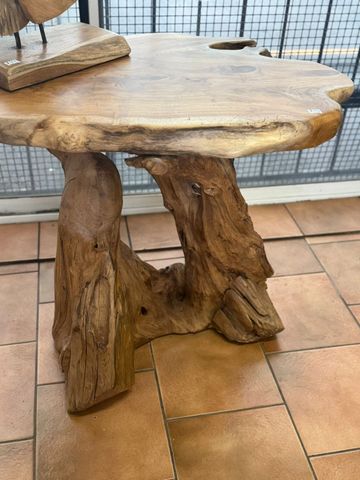 Rustic wooden table with natural, rough edges and sturdy trunk-like base.