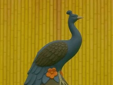 Decorative blue peacock statue on a vase against a bamboo backdrop.