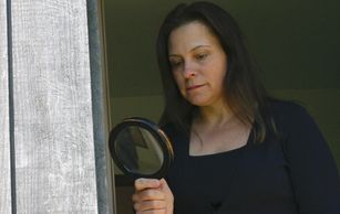 Woman using magnifying glass to examine a door