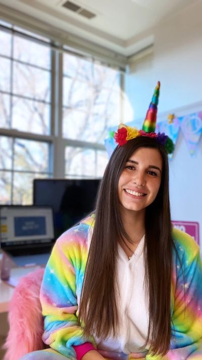Young woman wearing colorful unicorn-themed clothing and headband.