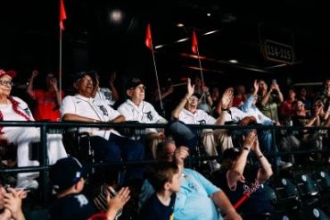 Fans cheering at a sports event with orange flags.