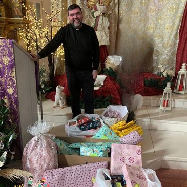 Hombre junto a regalos envueltos en una iglesia decorada.