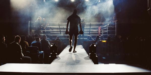 Boxeador entrando al ring con luces y humo.
