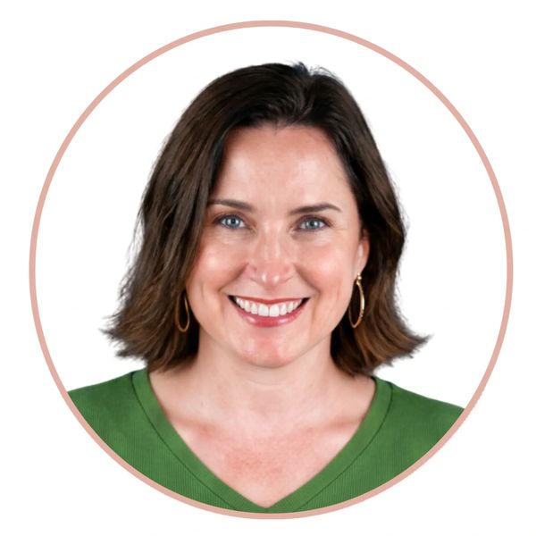 Smiling woman with short brown hair wearing a green top and hoop earrings.