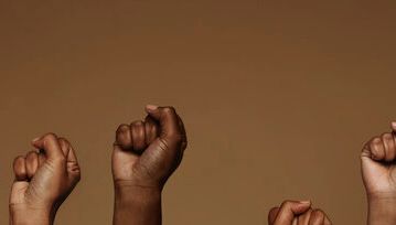 Raised fists of different sizes against brown background.