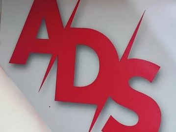 Red cutout letters ADs on white surface.