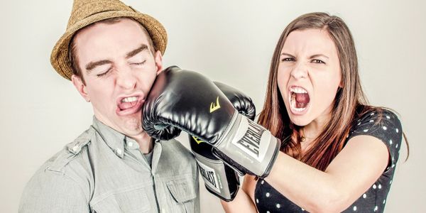 Woman punching man with boxing glove
