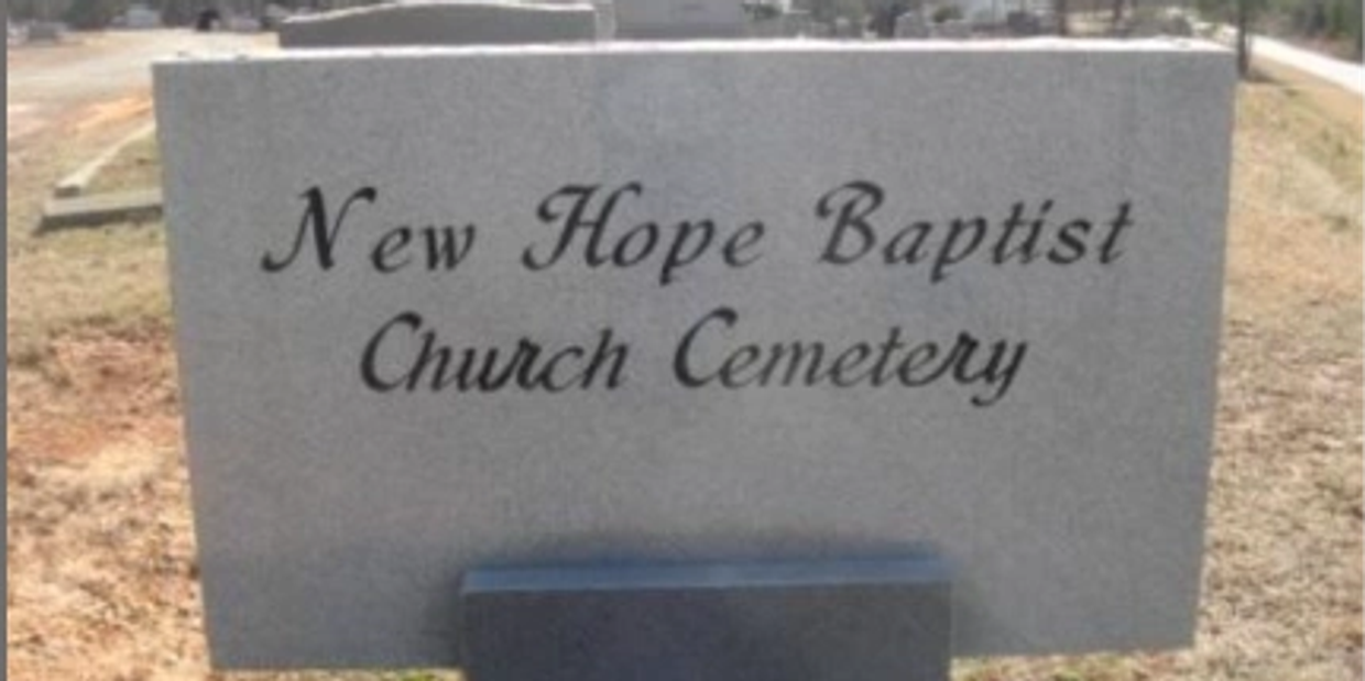 Stone sign for New Hope Baptist Church Cemetery in a rural setting.