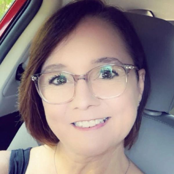 Smiling woman with glasses sitting in a car.