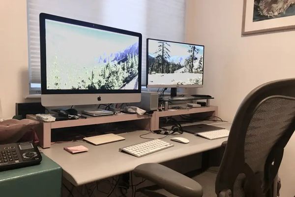 Das Bild zeigt einen Apple Computer und einen Windows PC nebeneinander auf einem Schreibtisch im hei
