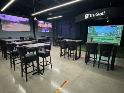 Tru Golf Simulator with multiple tables and chairs. Multiple large screen TVs