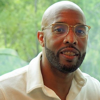 Man wearing glasses and a white shirt, smiling with braces.