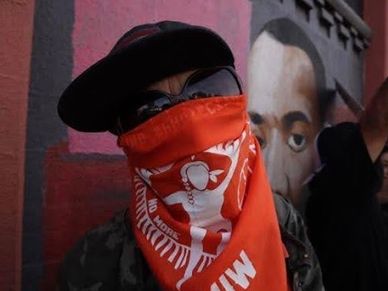 Person wearing a red bandana covering their face and sunglasses.