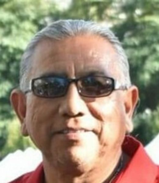 Man wearing black sunglasses and a red shirt outdoors.