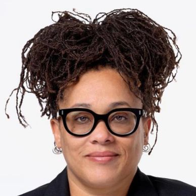 Person with glasses and dreadlocks styled up, wearing earrings.