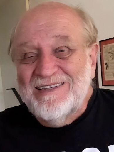 Smiling elderly man with white beard.