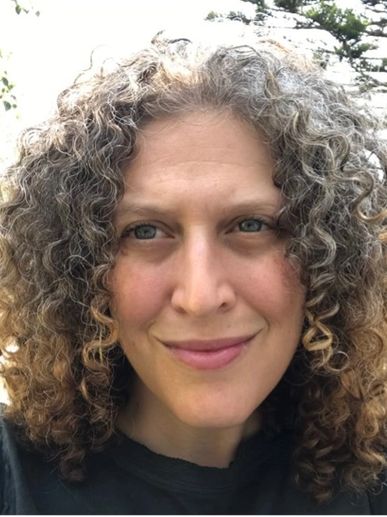 Smiling woman with curly hair outdoors.