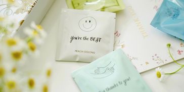 Tea packets with positive messages surrounded by flowers and a thank you card.